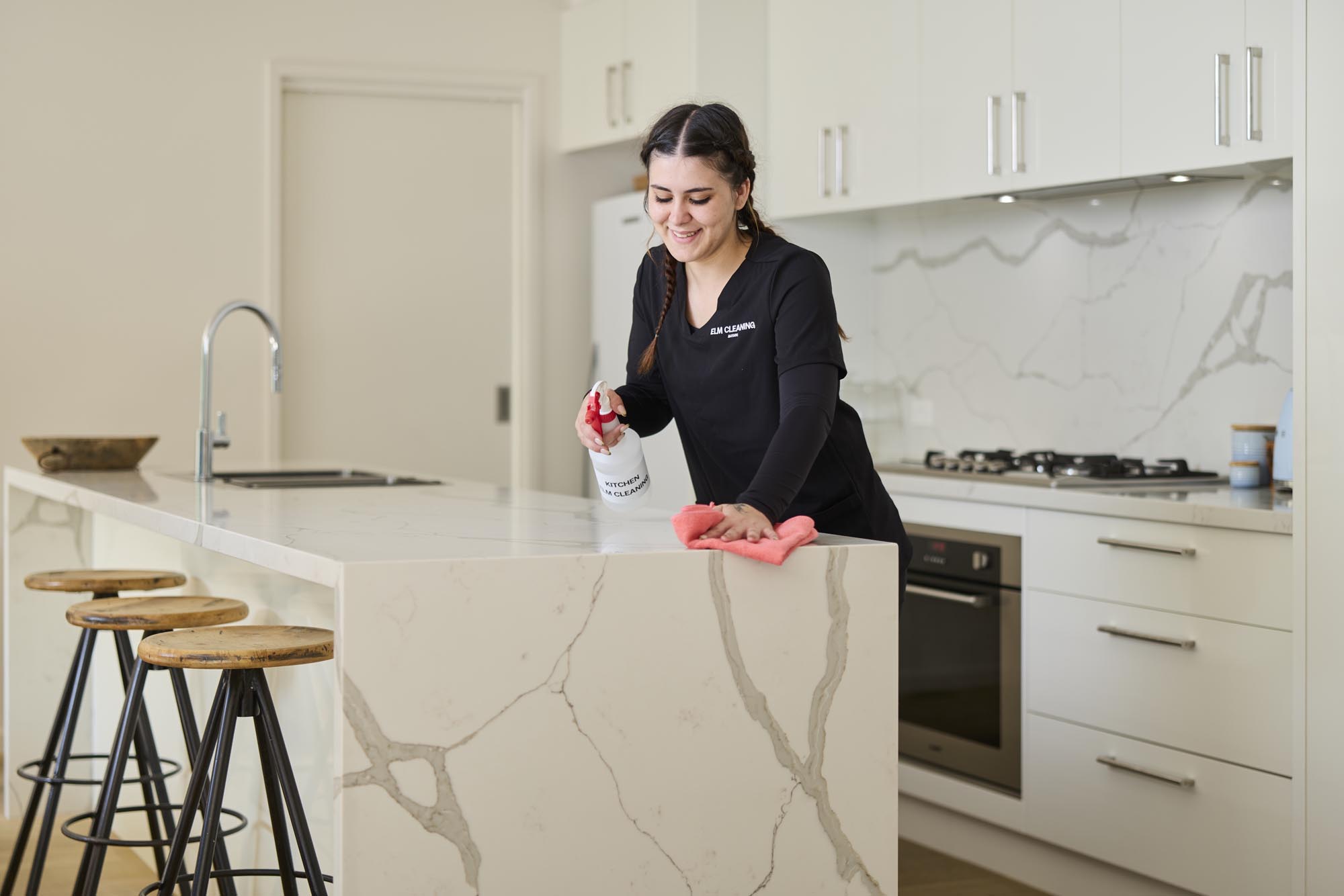 ELM cleaner wiping down a kitchen island bench
