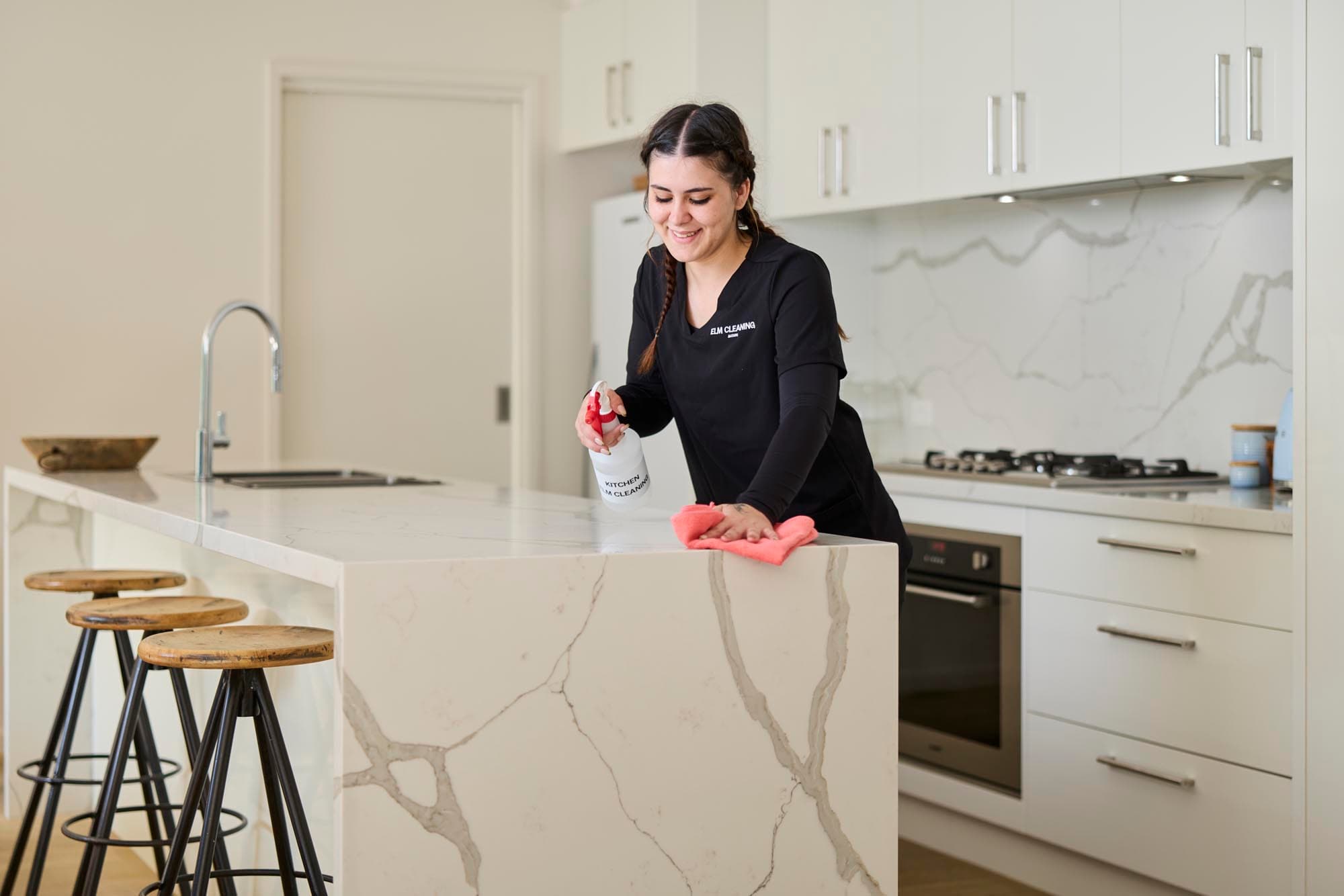 ELM cleaner wiping down a kitchen island bench