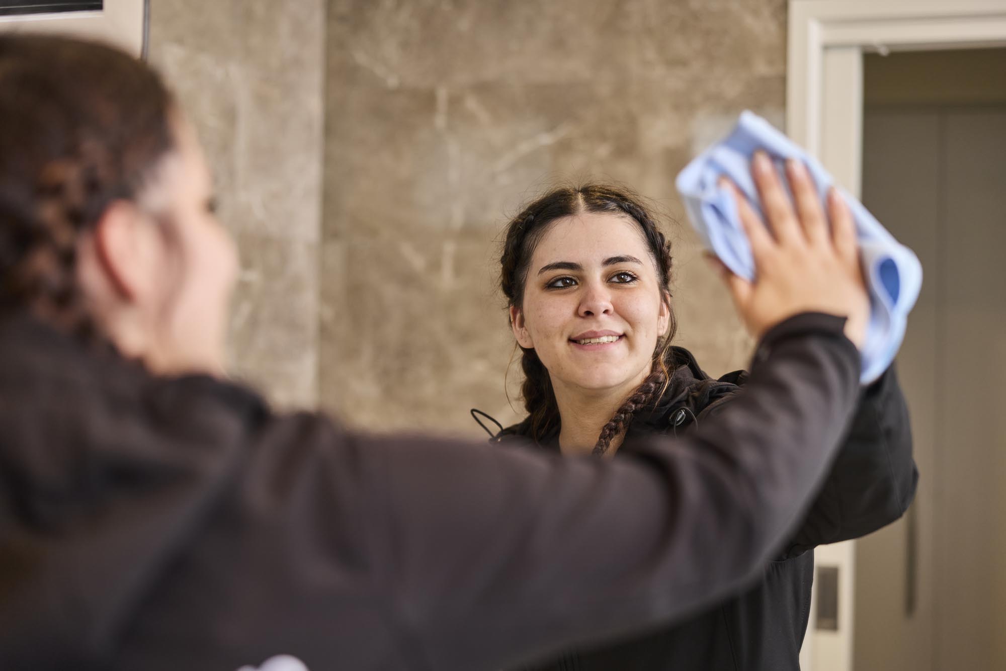 ELM cleaner wiping a bathroom mirror