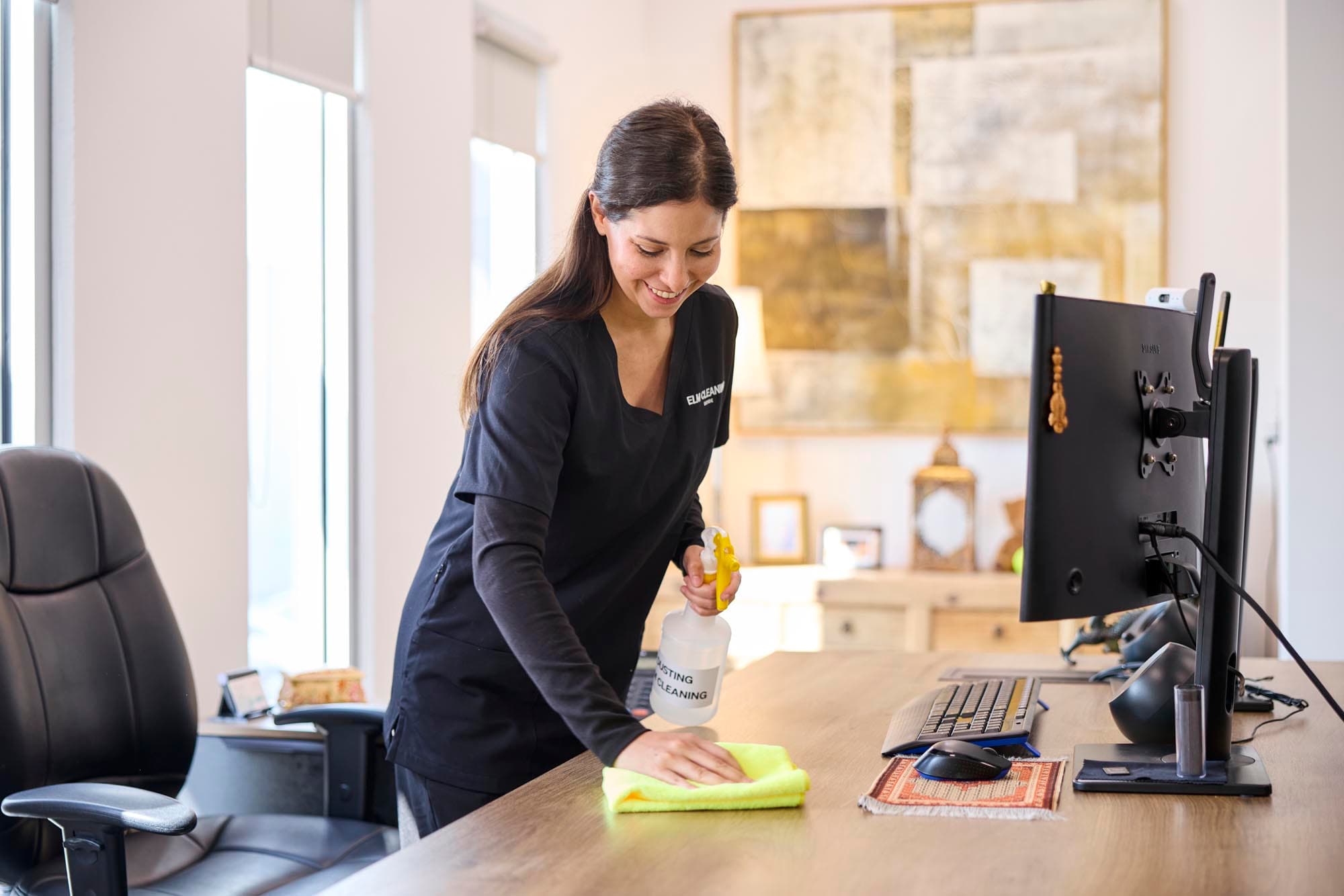 ELM Cleaning team member wiping down an office desk