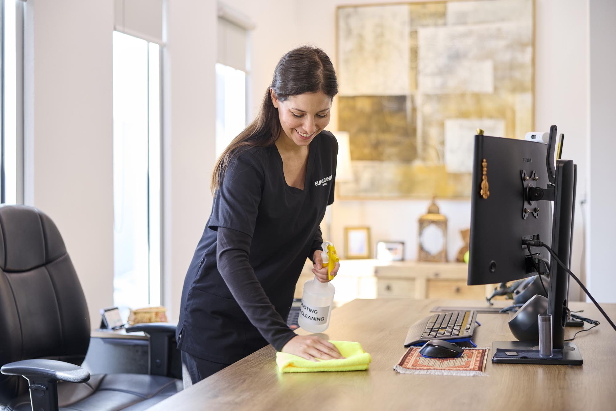 ELM Cleaning team member wiping down an office desk