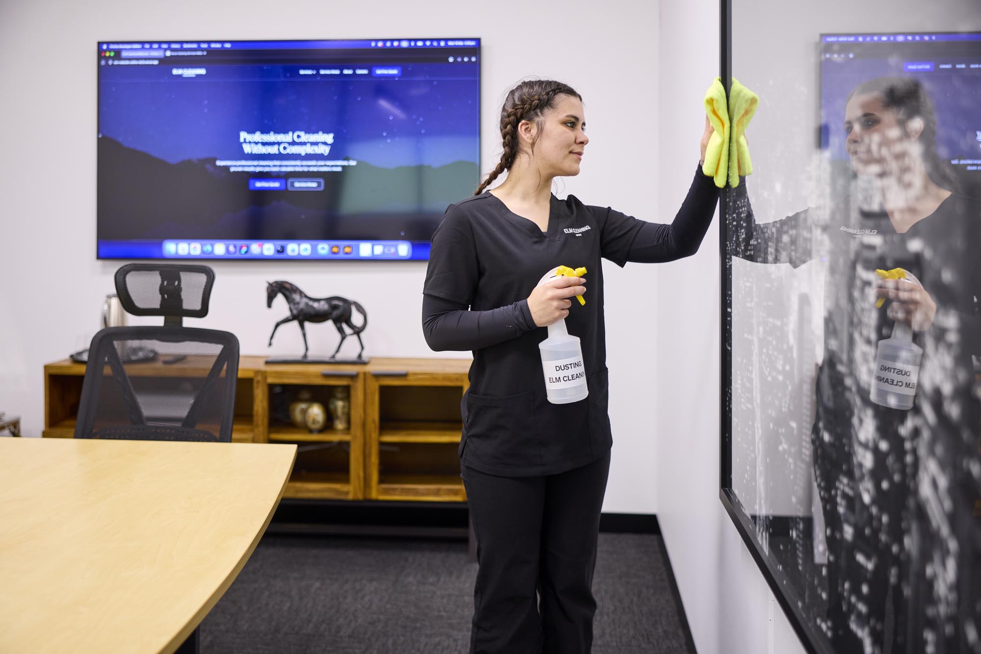 ELM Cleaning team member wiping glass partition in an office meeting room